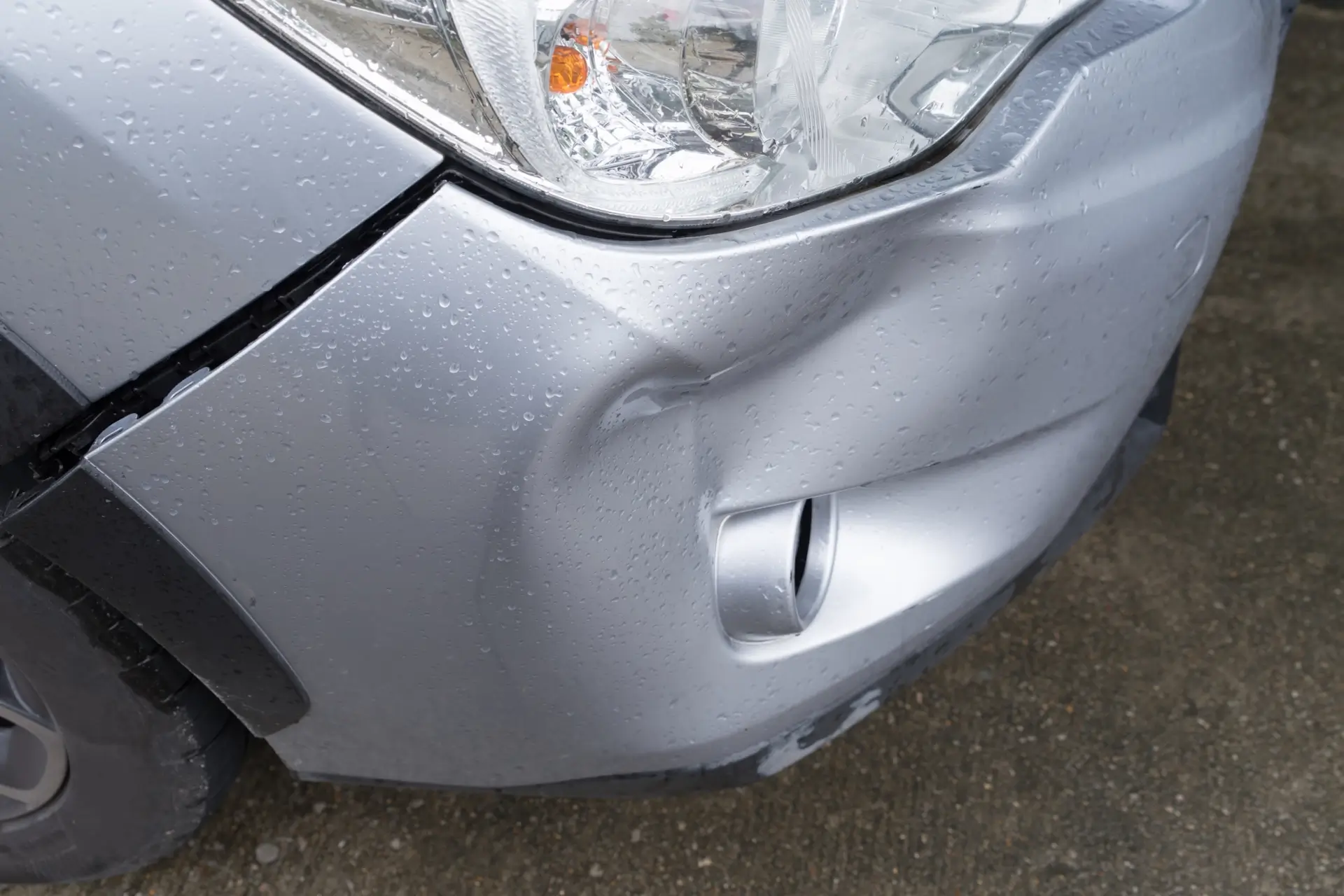 Damaged front bumper and headlight area after vehicle collision