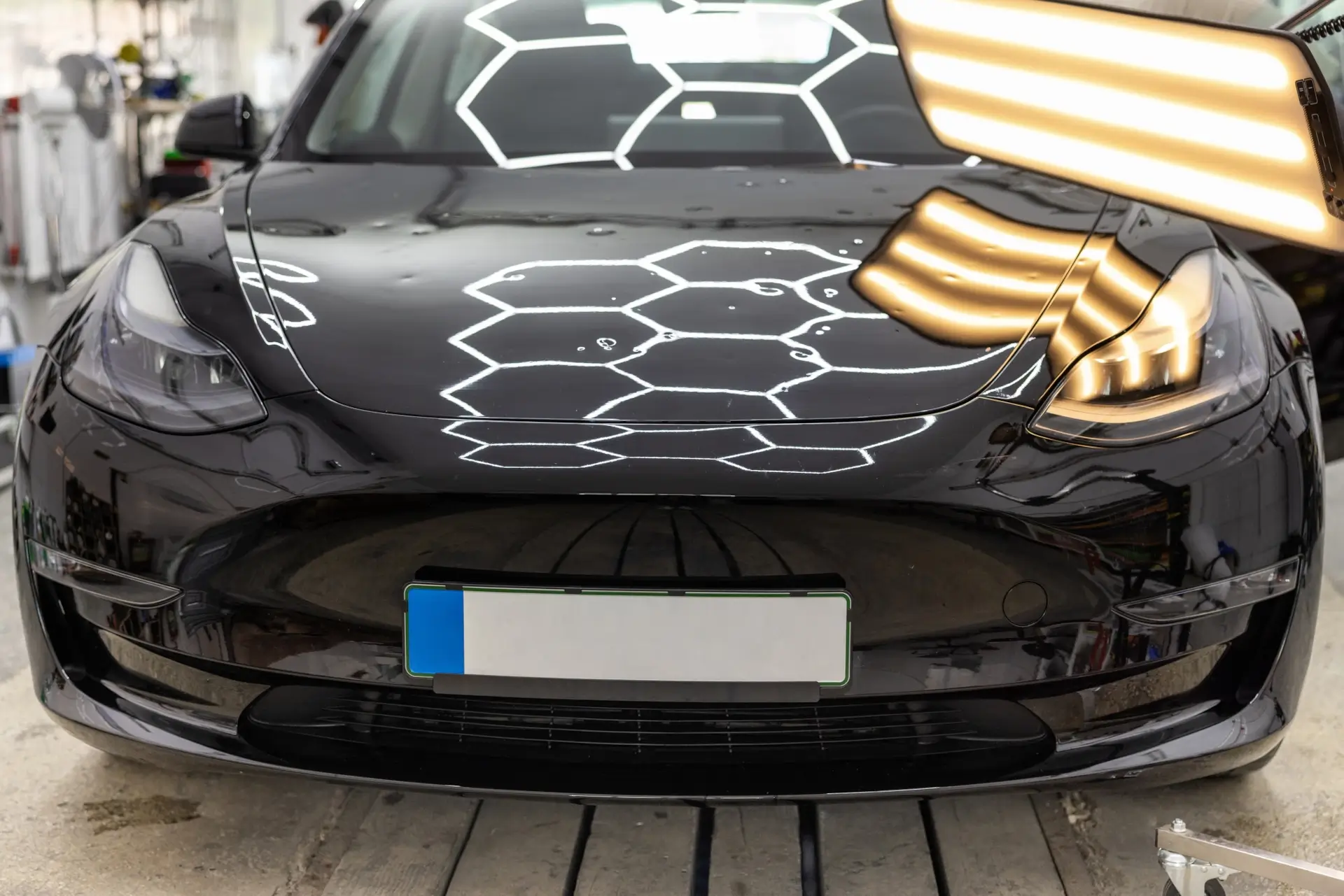 Tesla under high intensity lights to inspect for hail damage repair