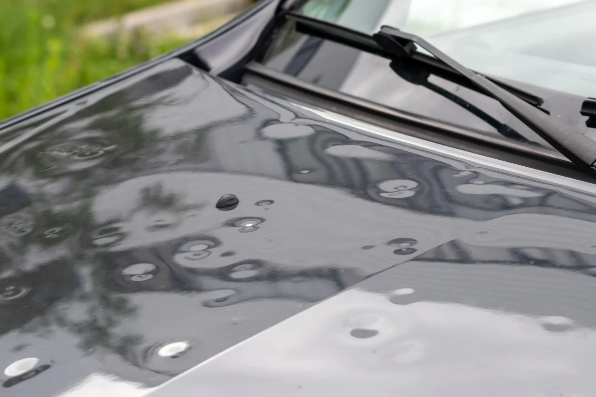 Black car hood showing damage from recent hail storm