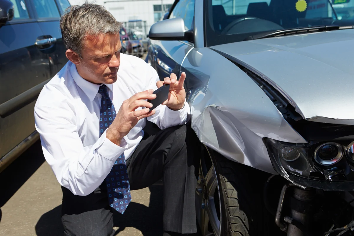 Insurance adjuster inspecting front-end vehicle damage after a car accident